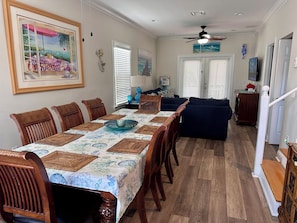A dining area with a long table, chairs, and a ceiling fan.