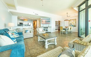 A spacious living area with a kitchen, dining area, and a large window providing natural light.