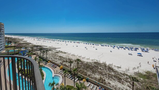 A beach resort with a swimming pool, beach chairs, and umbrellas.