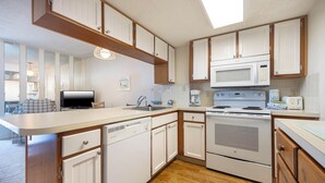 A compact kitchen with white cabinets, a microwave, an oven, and a dishwasher.
