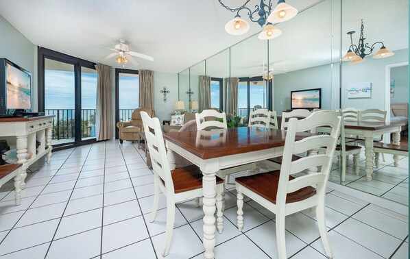 A dining room with a large table, white chairs, and a chandelier.