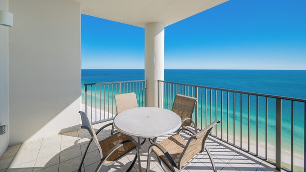 A balcony with a round table and chairs, overlooking a clear blue sea. - The Oasis at Orange Beach, formerly known as Phoenix West II, Unit 2405 (Orange Beach)