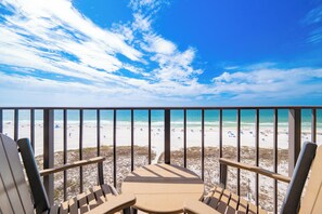 Un balcon donnant sur une plage, avec une table et des chaises.