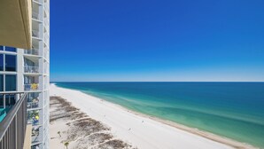 A high-rise hotel overlooking a beach with clear turquoise waters and a sandy shore.