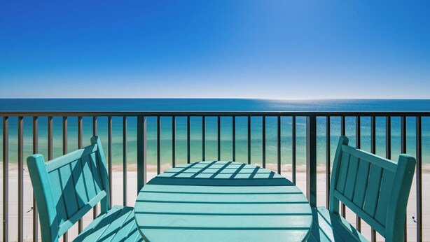 A balcony with a view of the ocean, featuring a table and two chairs.