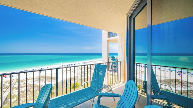 A balcony with a view of the beach, two chairs, and a glass door. - 7th Floor Two Bedroom ~ Phoenix East (Orange Beach)