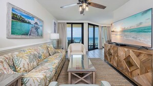 A living room with a sofa, a coffee table, a TV, and a ceiling fan.