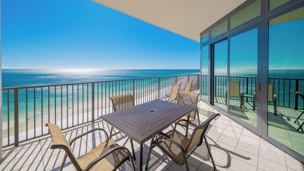 A balcony with a table and chairs, overlooking a beach and ocean. - The Oasis at Orange Beach, formerly known as Phoenix West II, Unit 1503 (Orange Beach)