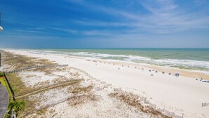 A beach with a wooden fence, sandy beach, and ocean waves. - *Two Bedroom Gulf Front Condo at Phoenix 9* (Orange Beach)