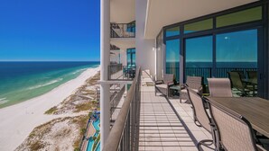 A balcony with a view of the beach and ocean, furnished with chairs and a table. - The Oasis at Orange Beach, formerly known as Phoenix West II, Unit 1710 (Orange Beach)