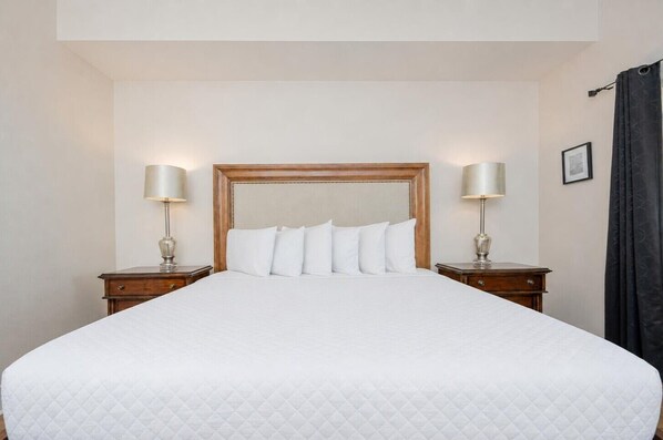 Une chambre d’hôtel avec un grand lit, deux tables de chevet et deux lampes.