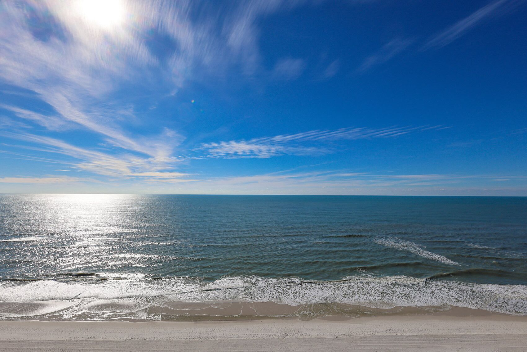Een strand met een heldere lucht en een rustige zee.