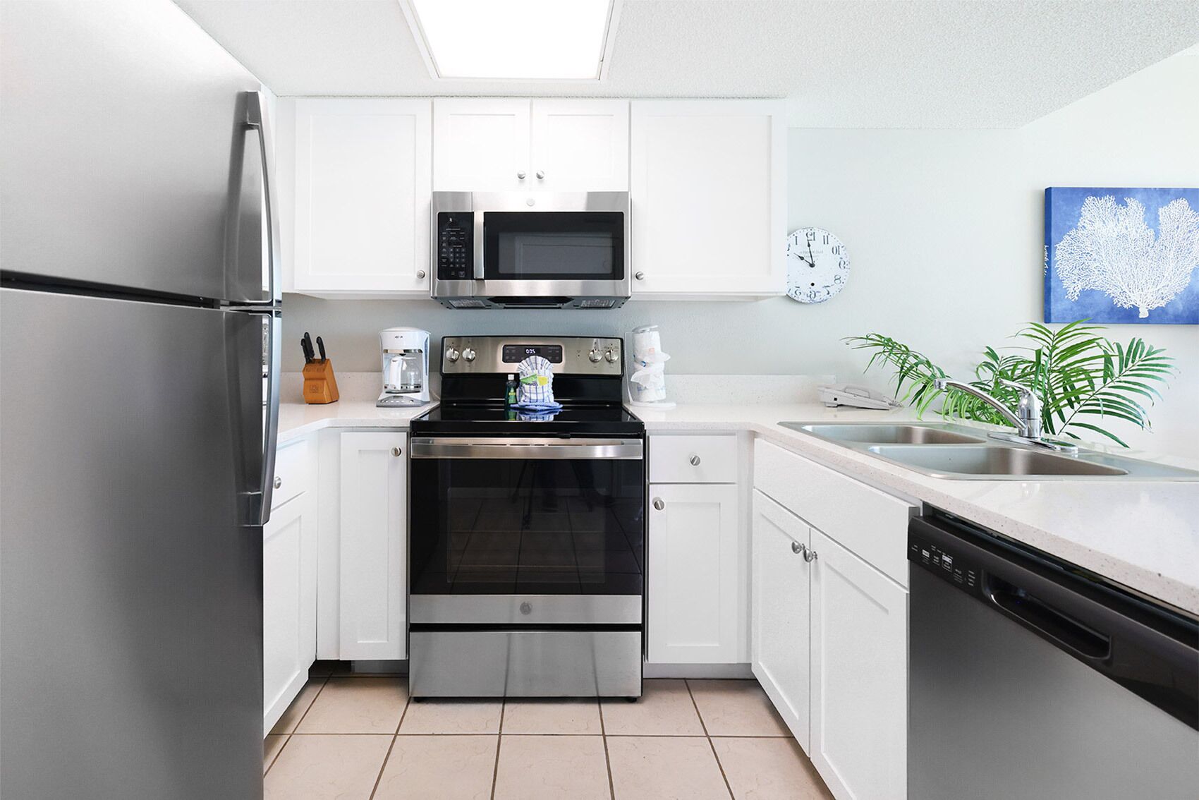 A modern kitchen with stainless steel appliances, white cabinetry, and a tiled floor.