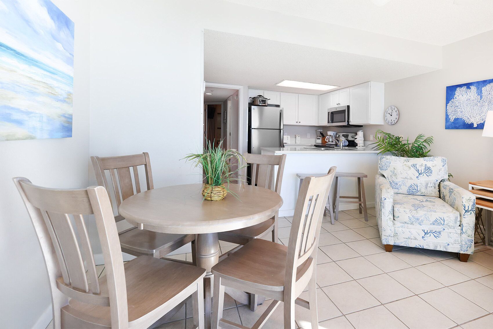 Una cocina moderna con armarios blancos, una isla central y un comedor con sillas de madera y una mesa redonda.