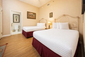 A hotel room with two beds, a wooden floor, a toilet, and a painting on the wall. - 2 BR @ Phoenix VII - *Reserved Parking* (Orange Beach)