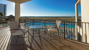 A balcony with a pool, two chairs, and a table. - 2 BR @ Phoenix VII - *Reserved Parking* (Orange Beach)