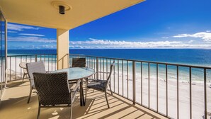 A balcony with a table and chairs overlooking a beach.