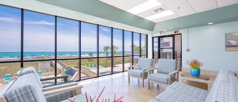 A spacious room with large windows, a pool view, and a seating area with a plant.