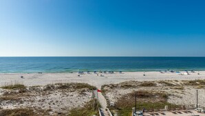A beach with white sand, blue umbrellas, and a clear sky. - Island Winds East Condo 404 *BeachFront* (Gulf Shores)