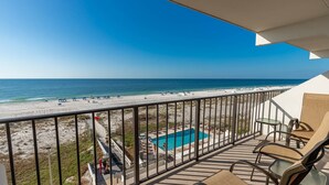 A balcony with a pool, beach view, and outdoor seating. - Island Winds East Condo 404 *BeachFront* (Gulf Shores)