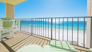 Ein Balkon mit Blick auf einen Strand, ausgestattet mit Geländer und mehreren Stühlen.