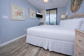 A bedroom with a bed, a television, and artwork on the wall.