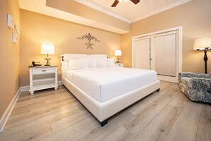 Un dormitorio con una cama grande, mesitas de noche con lámparas, un armario y un ventilador de techo.