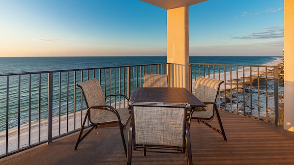 Un balcon avec une table et des chaises donnant sur l’océan.