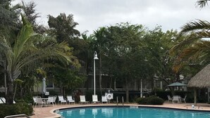 A swimming pool with a brick deck, surrounded by lounge chairs and palm trees. -  Casa Capri Beautiful Tropical with 3 King Suites - 2 miles to beach (Key West)