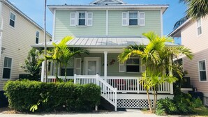 A two-story house with a front porch, white railings, and a small staircase leading to the entrance. -  Casa Capri Beautiful Tropical with 3 King Suites - 2 miles to beach (Key West)