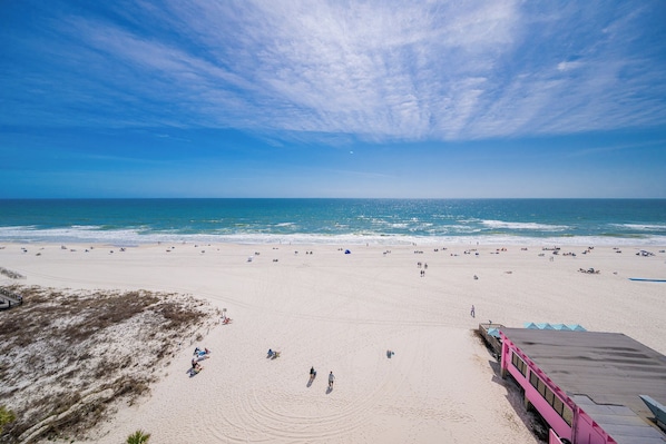 A beach with a clear sky, sandy shore, and a few people.