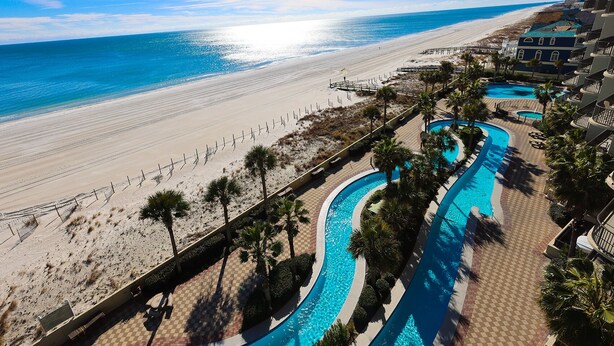 Ein Resort mit Blick auf den Strand, einem Poolbereich und einer Strandpromenade.