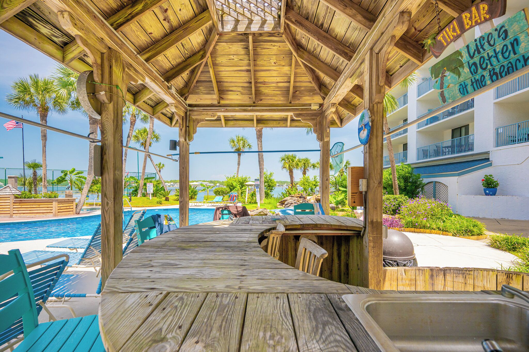 A wooden deck with a pool, bar area, and outdoor seating.