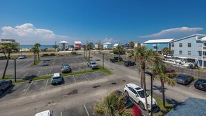 Ein Parkplatz mit mehreren Autos, Palmen und Gebäuden mit Blick auf den Strand.