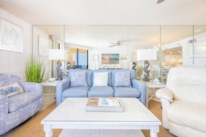 A living room with a sofa, armchair, coffee table, and a TV.
