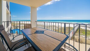 A balcony with a table and chairs, overlooking a beach and ocean. - RELAX on the BEACH! **Gulf Front 2 Bedroom at Phoenix III (Orange Beach)