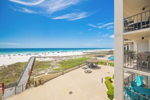 A beachfront hotel with a pool, outdoor seating, and a view of the beach.