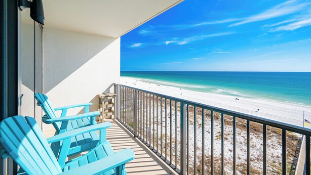 Un balcon avec des chaises bleues donnant sur une plage.