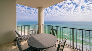 A balcony with a table and chairs, overlooking a beach and ocean. - The Oasis, Unit 2209 — Luxury 3BR/4BA Gulf-Front Condo with Resort Amenities (Orange Beach)