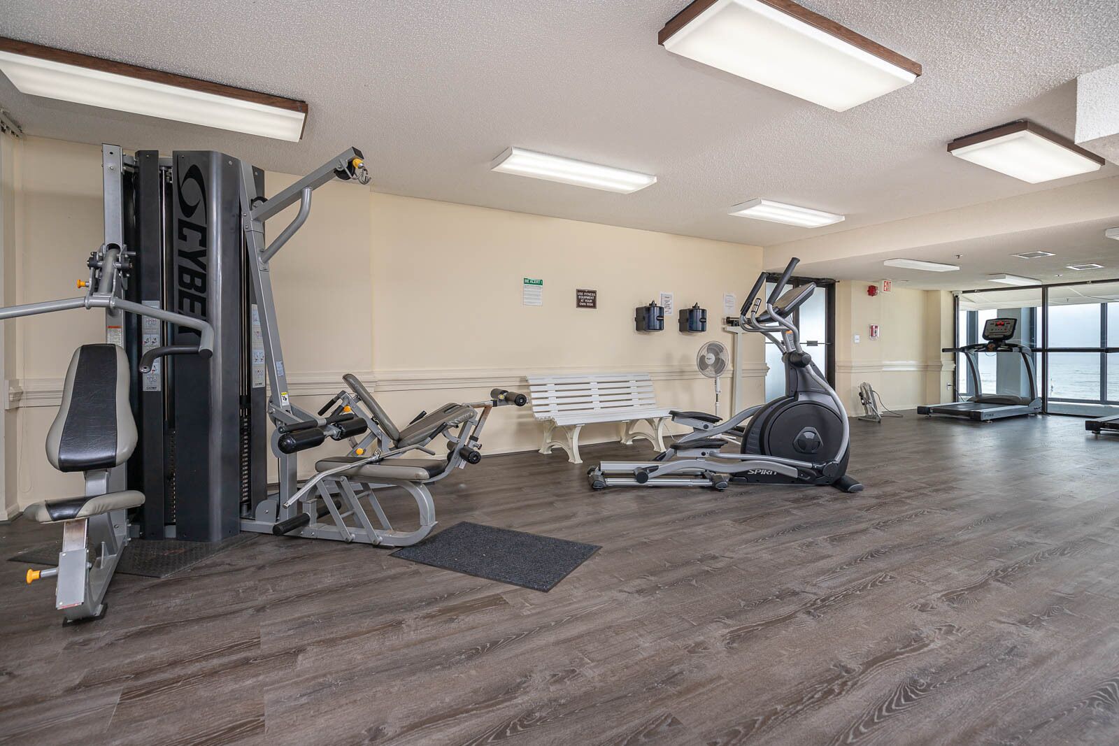 Un gimnasio con máquinas de cardio, equipo de pesas y una banca.