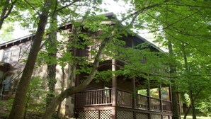 A wooden cabin with a balcony, surrounded by trees. - ARCADE GAMES💥Recent Peacock Sightings💥May weekdays up till the 21th $75 to $85 (Pigeon Forge)