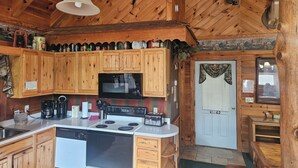 A wooden cabin kitchen with a stove, microwave, and wooden cabinets. - ARCADE GAMES💥Recent Peacock Sightings💥May weekdays up till the 21th $75 to $85 (Pigeon Forge)
