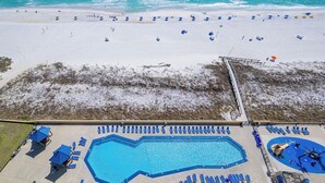 Una playa con piscina, tumbonas y sombrillas.