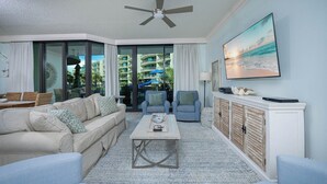 Una sala de estar moderna con un sofá beige, sillones azules, una mesa de centro y un aparador con objetos decorativos.
