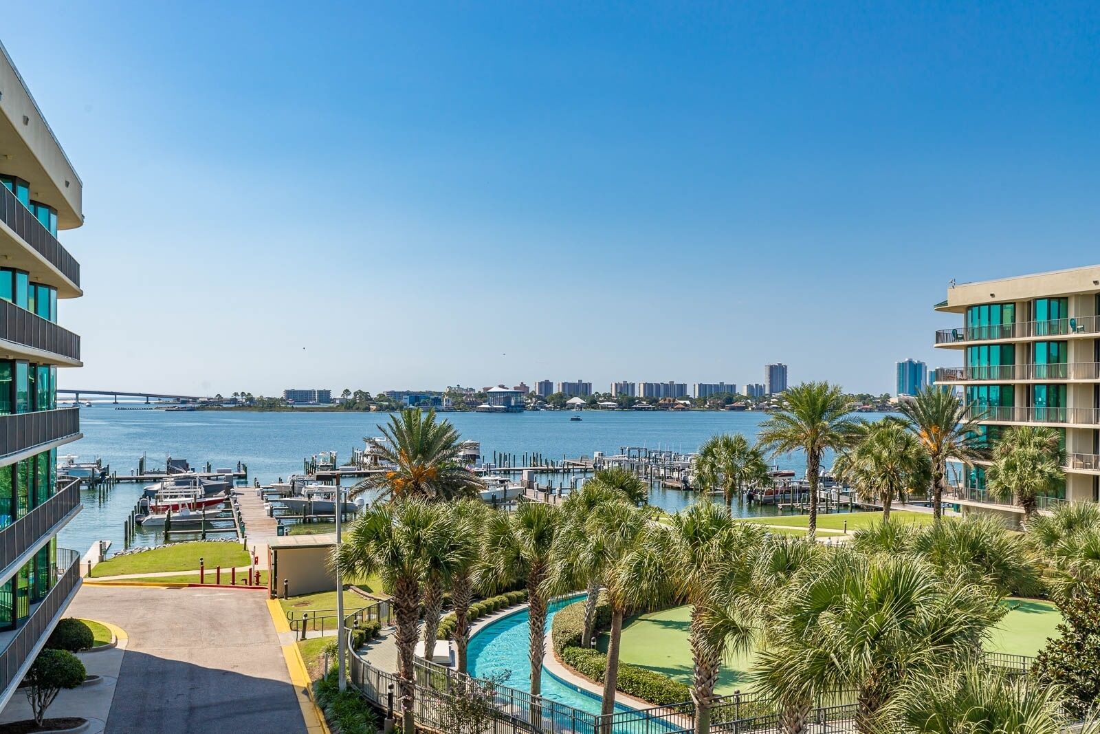 Ein Hotel am Wasser mit Pool, Palmen und einem Hafen.