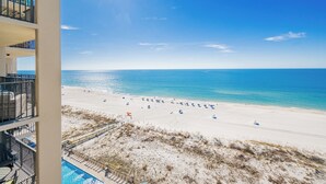 Une plage avec un ciel dégagé, une piscine et un bâtiment doté de balcons.