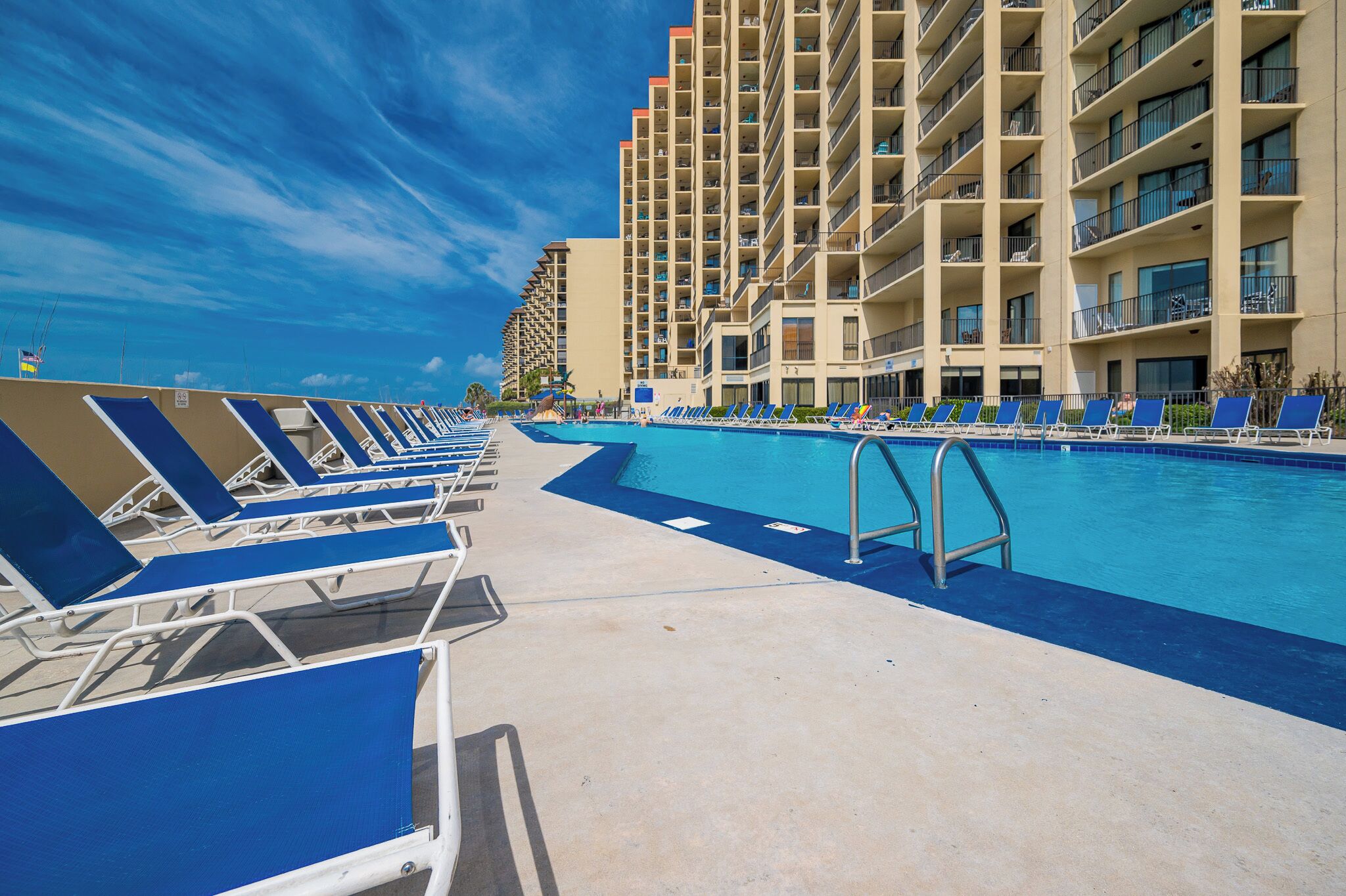 Lounge at the poolside with ample chairs and enjoy the beautiful beachfront view from your vacation rental at Phoenix V