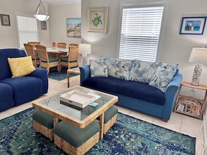 A living room with a blue sofa, wicker coffee table, and patterned cushions.