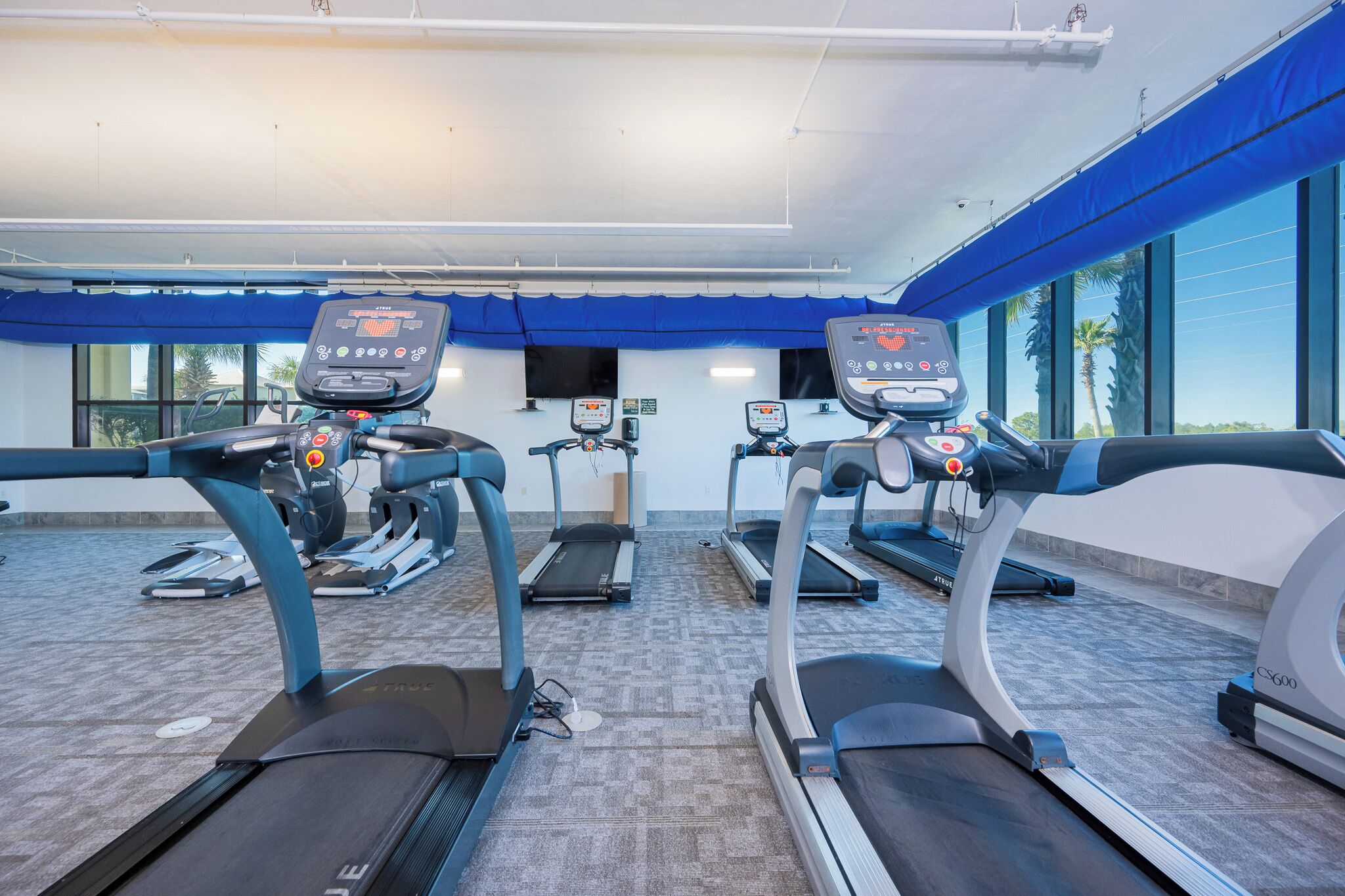 A gym with treadmills, stationary bikes, and a weight machine.
