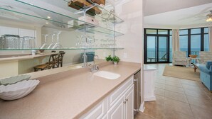 Une cuisine moderne dotée d’un îlot central avec façade en verre, d’une grande fenêtre et d’une vue sur l’extérieur.